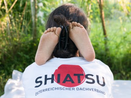 Kinderfüße auf der Schulter der Shiatsupraktikerin